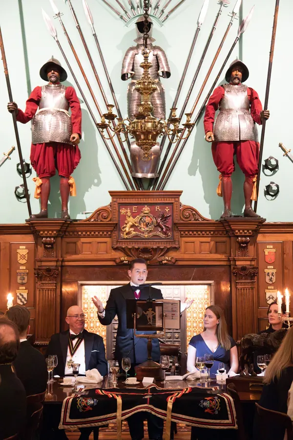 Liam Randall delivering a Coopers' Company speech, flanked by the Company's yeomen guards.